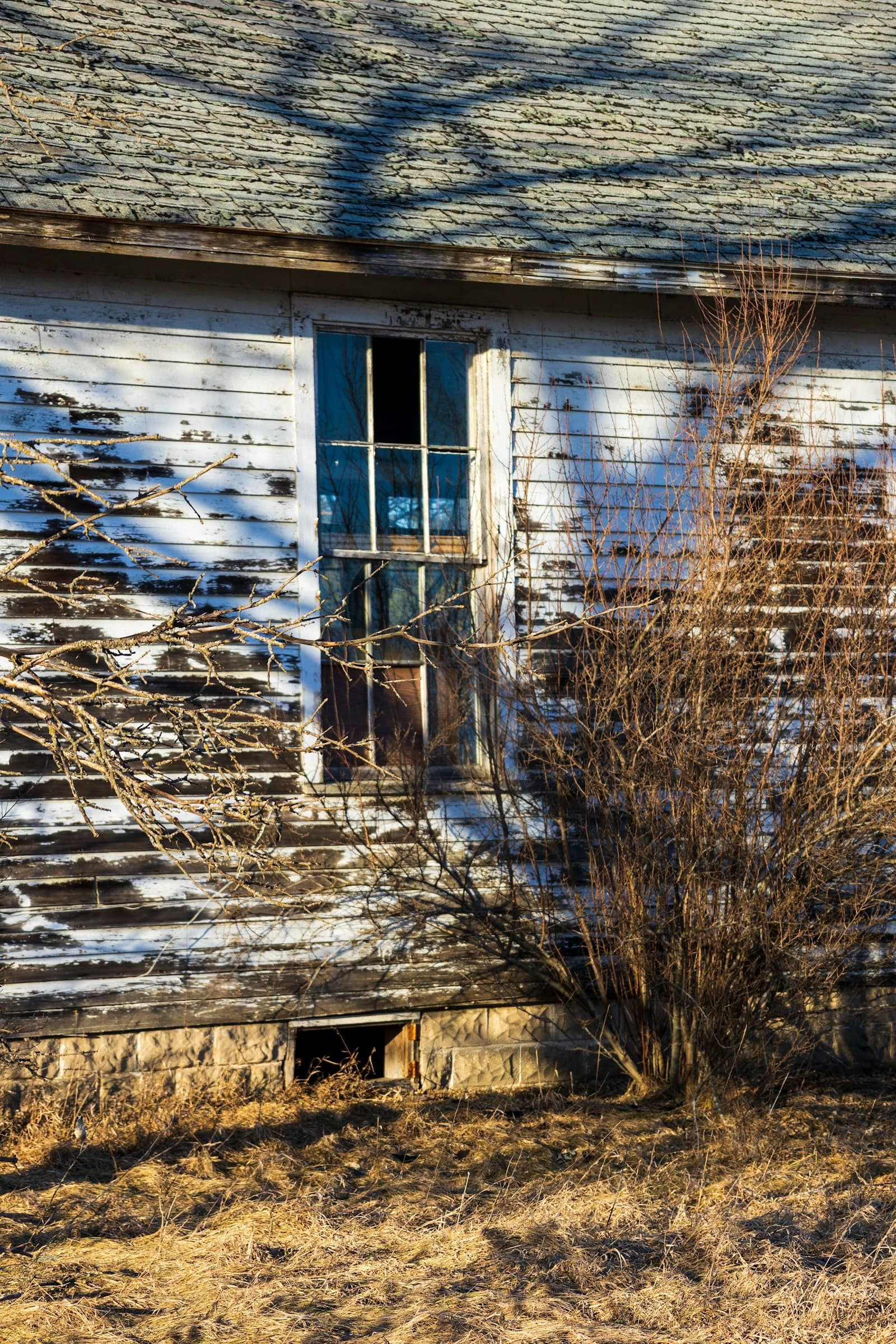 Weathered siding and an old failing window on a Minnesota farmhouse
