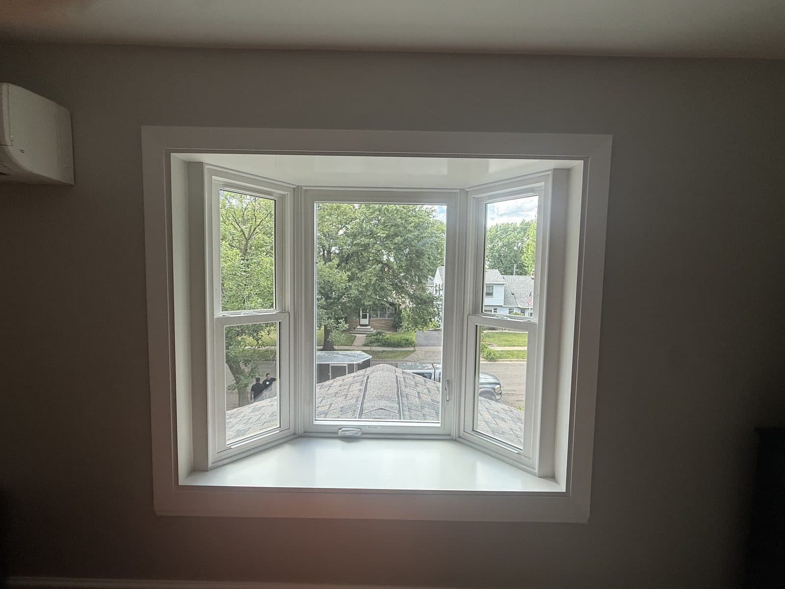 New bay window with white casing and seat board, centered in a quiet room