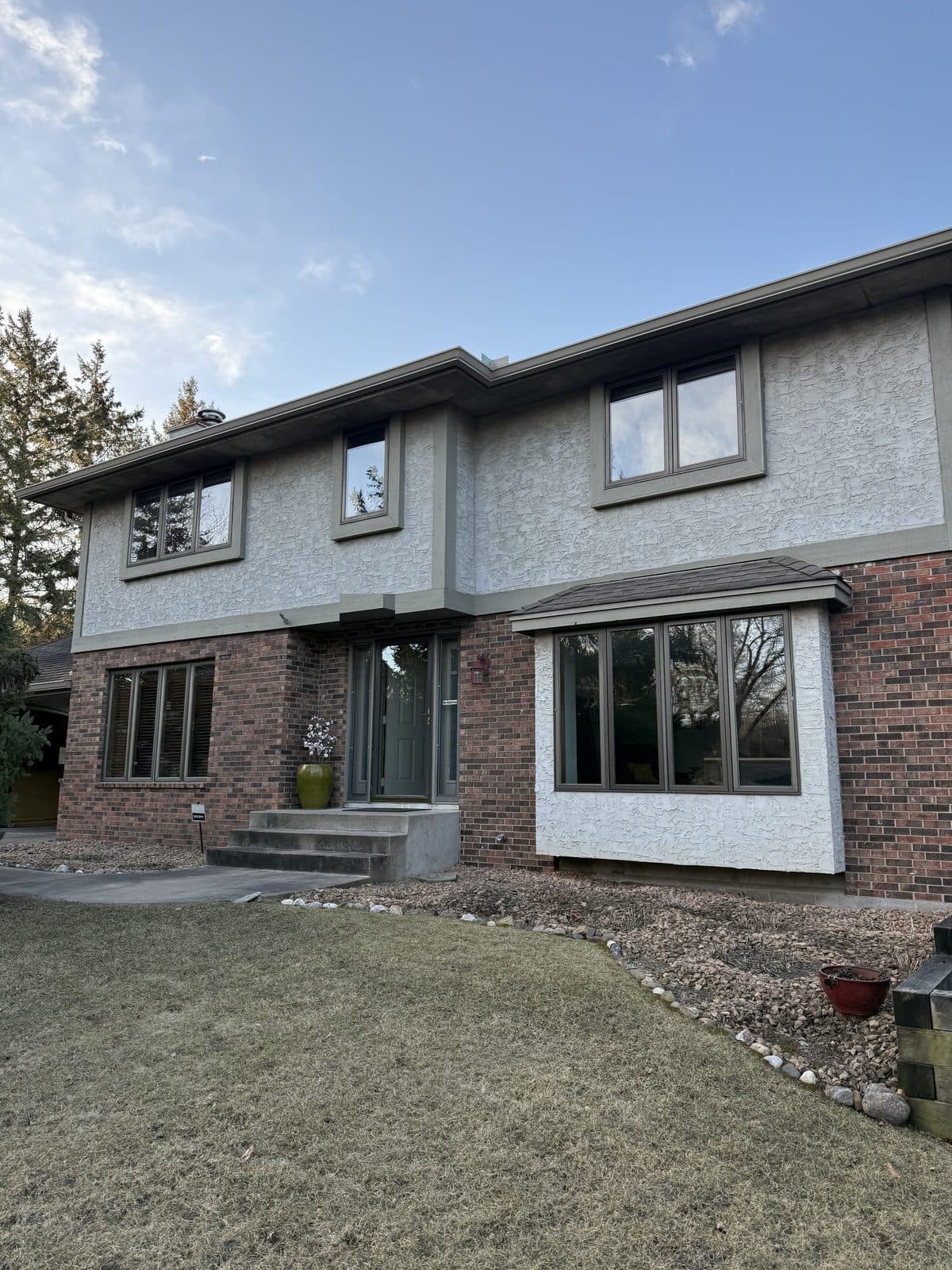 Front of a brick and stucco two-story with all-new bronze windows and a bay
