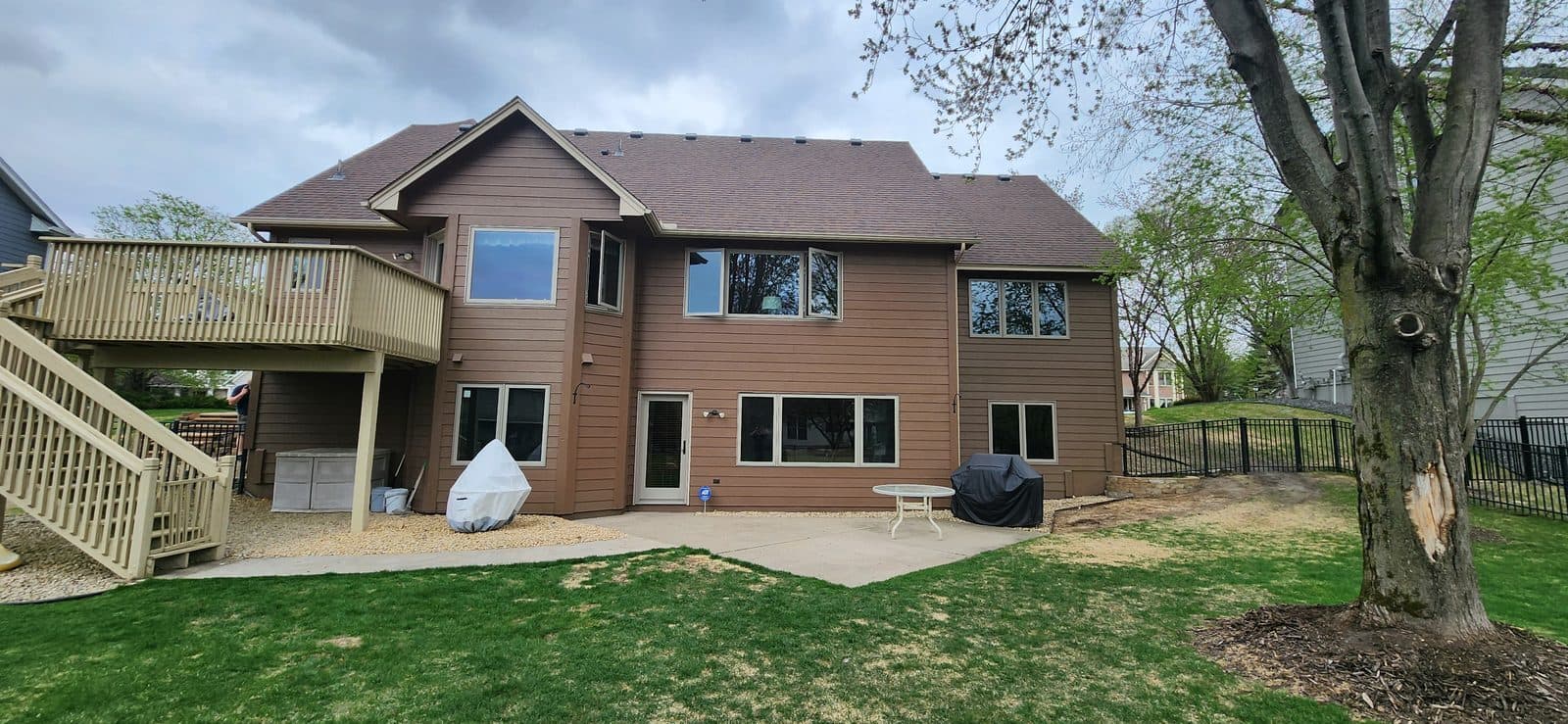 Rear of a brown two-story home with all-new white windows and a deck