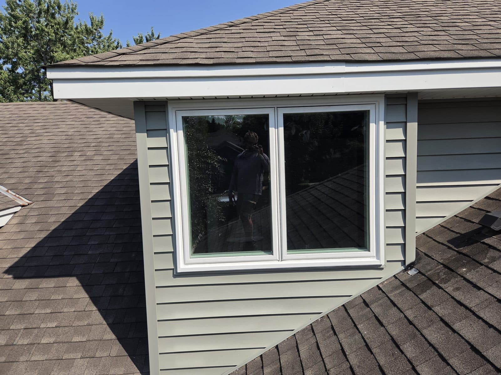 Roof dormer with a new casement window pair in sage siding, architectural shingles around it