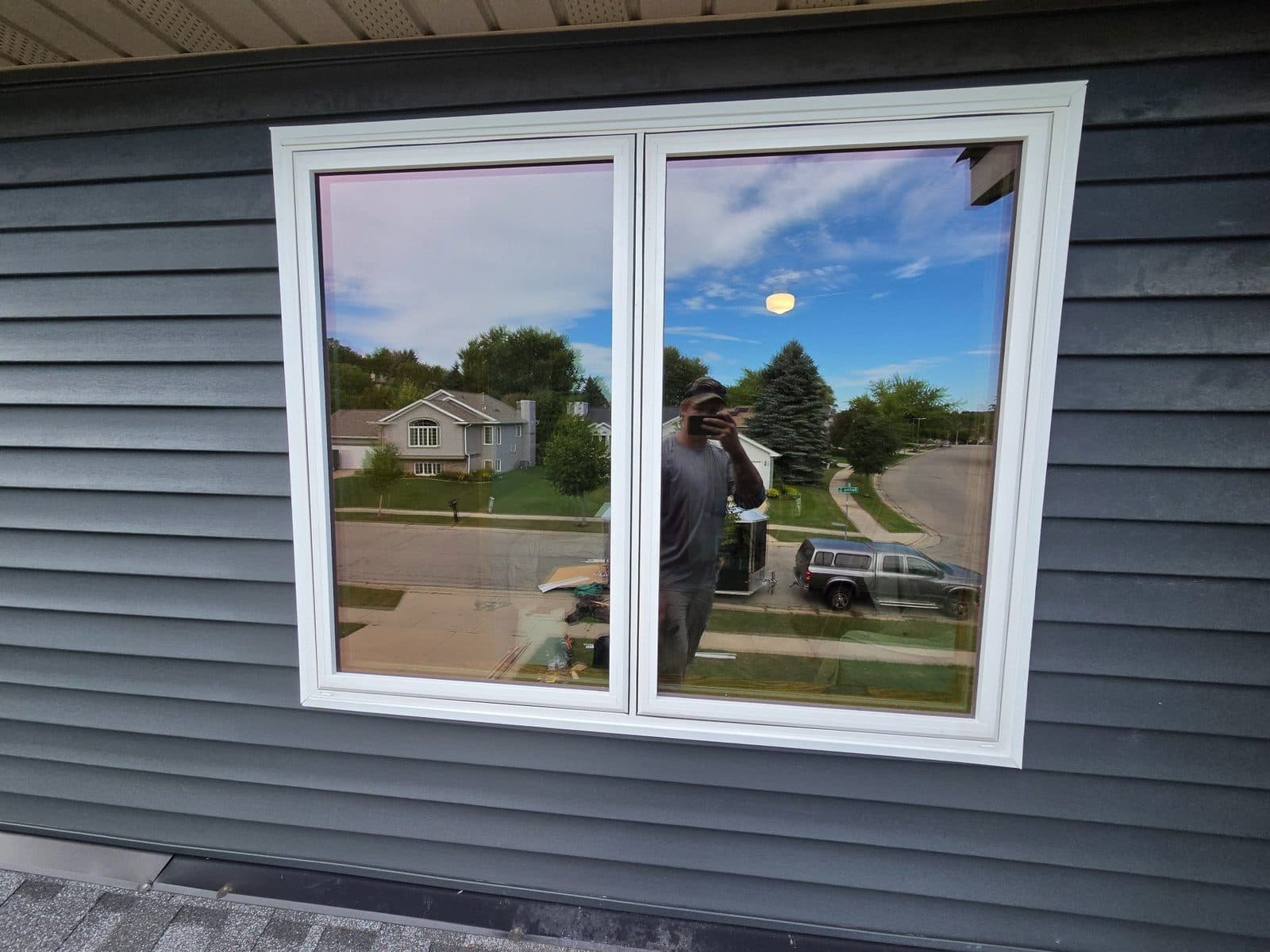 White double casement window on dark gray lap siding