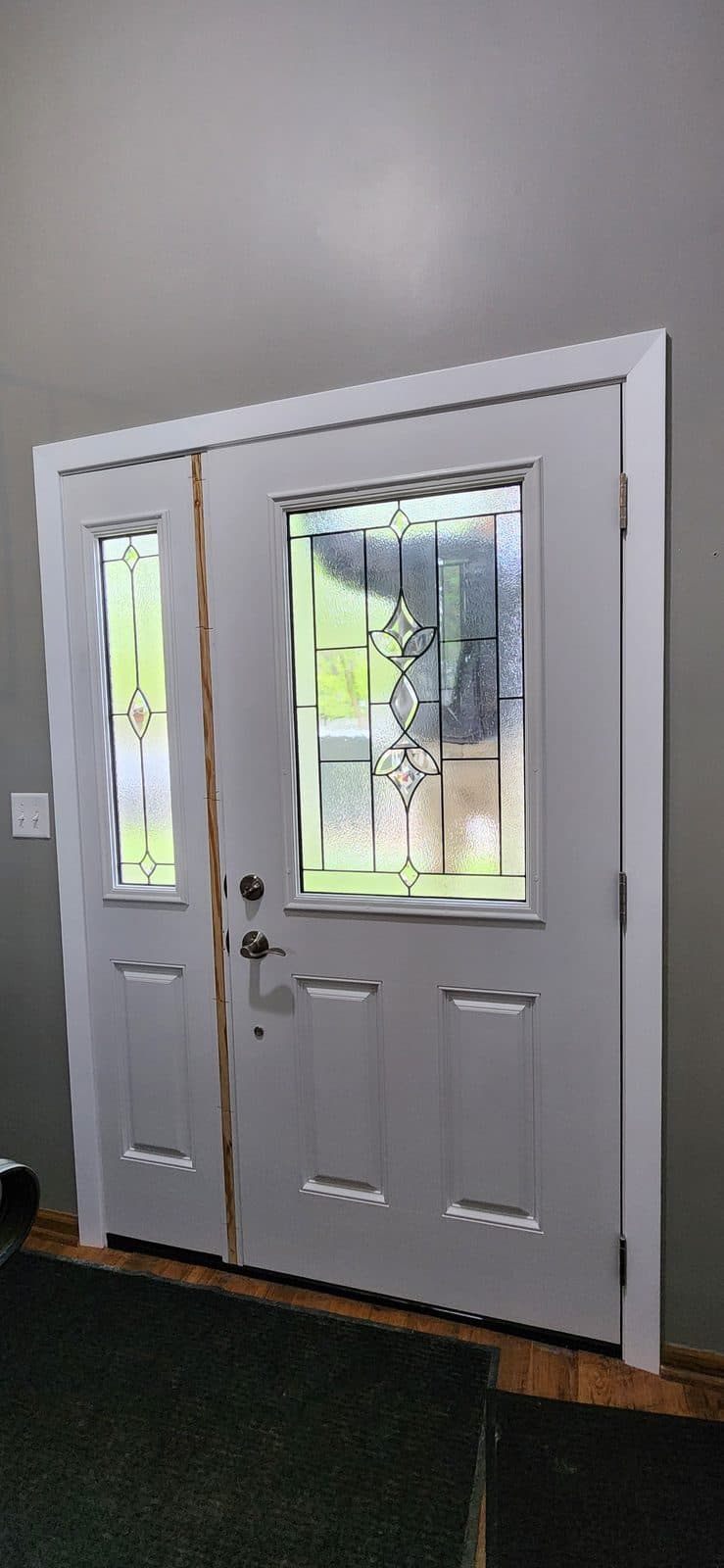 Finished white entry door with decorative glass and a sidelite, seen from inside