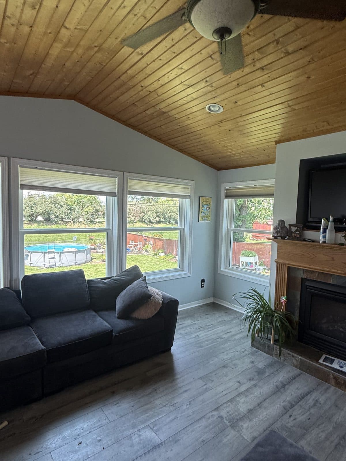 Living room with new windows beside the fireplace under a wood ceiling