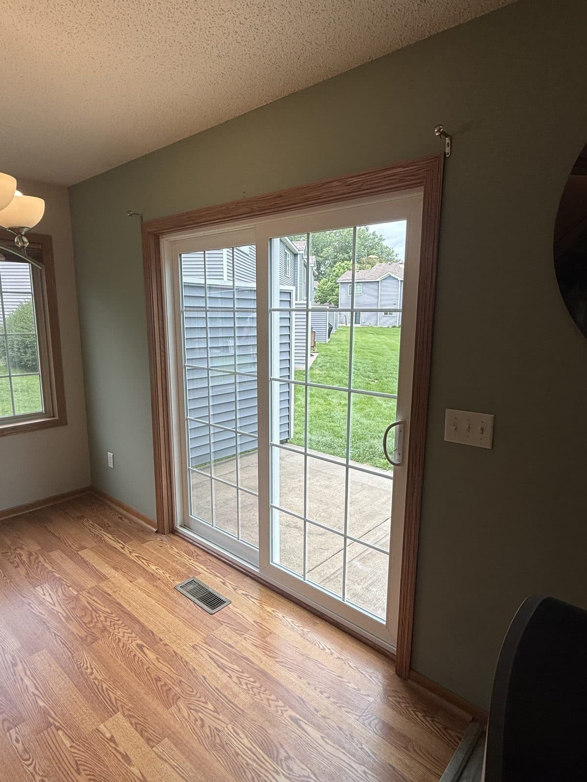 Oak-trimmed gridded patio door from inside, hardwood floor and green walls