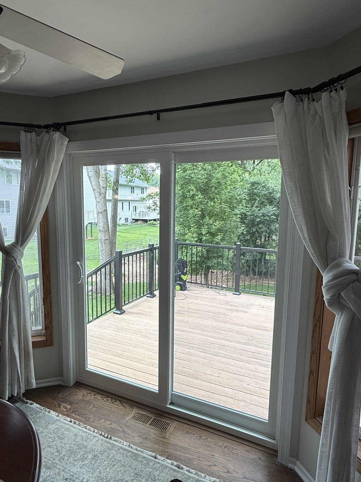 Oak-trimmed patio door with sheer curtains opening onto a deck