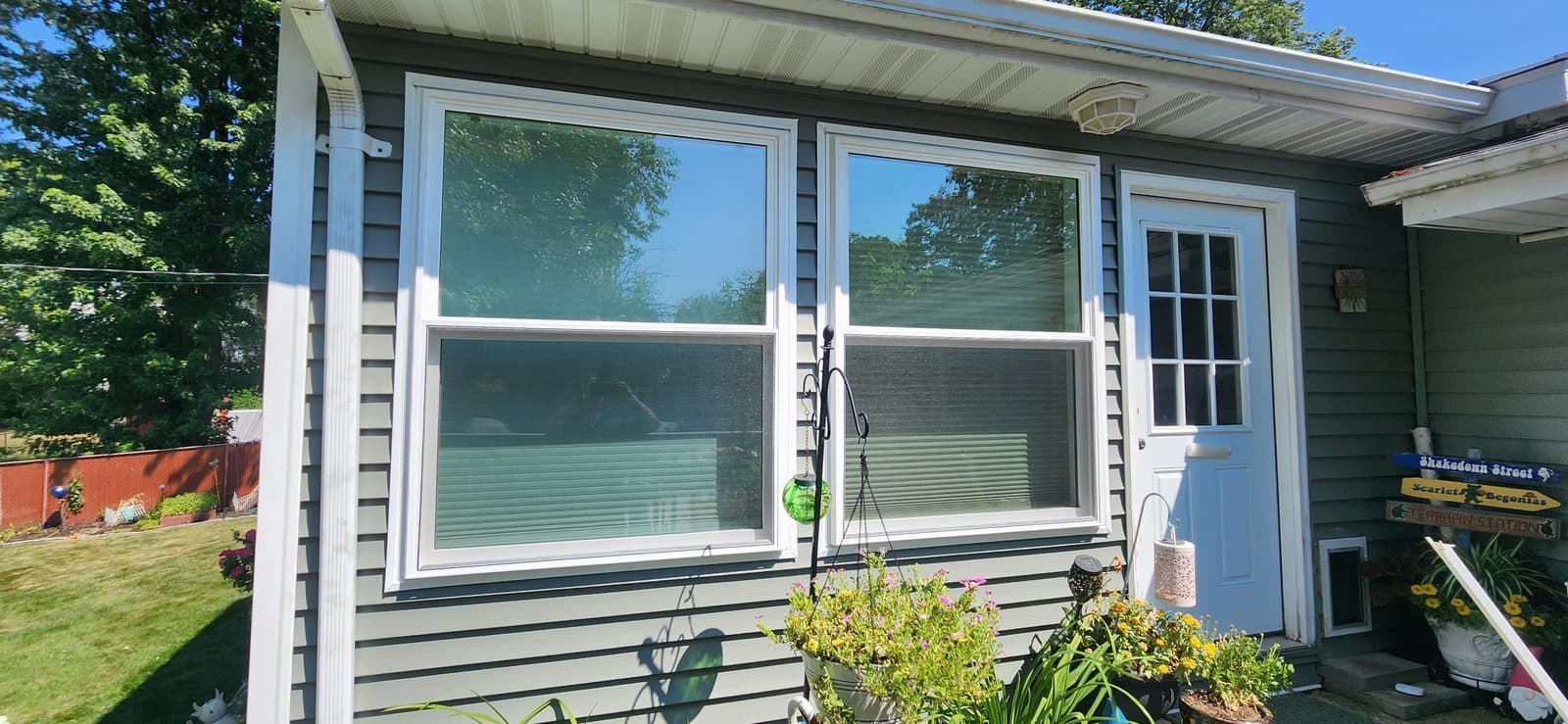 New white picture window with flanking double-hungs and a white storm door on a green-sided home