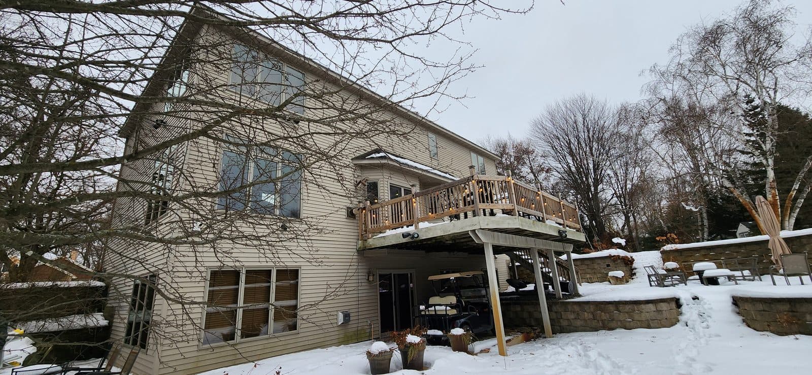 Rear of a two-story home with a raised deck and new windows in winter evening light