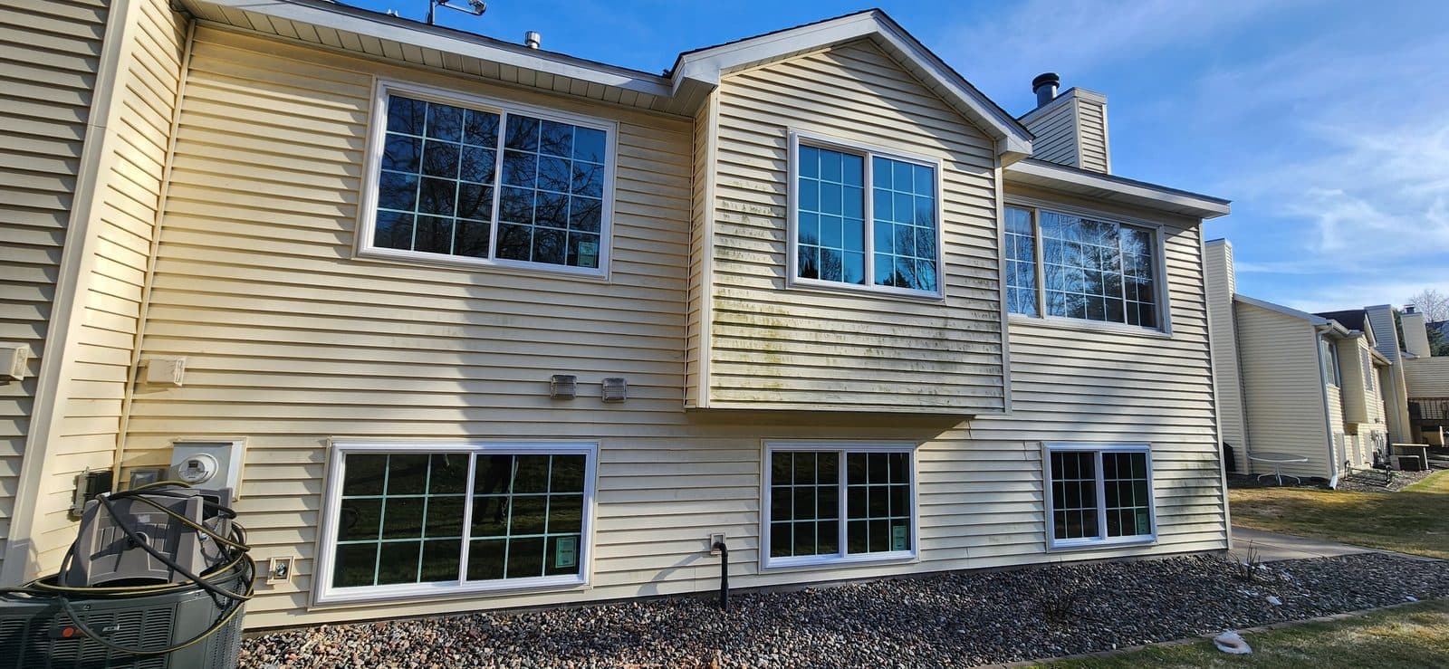 Rear of a cream-sided home with new white grid windows on both levels