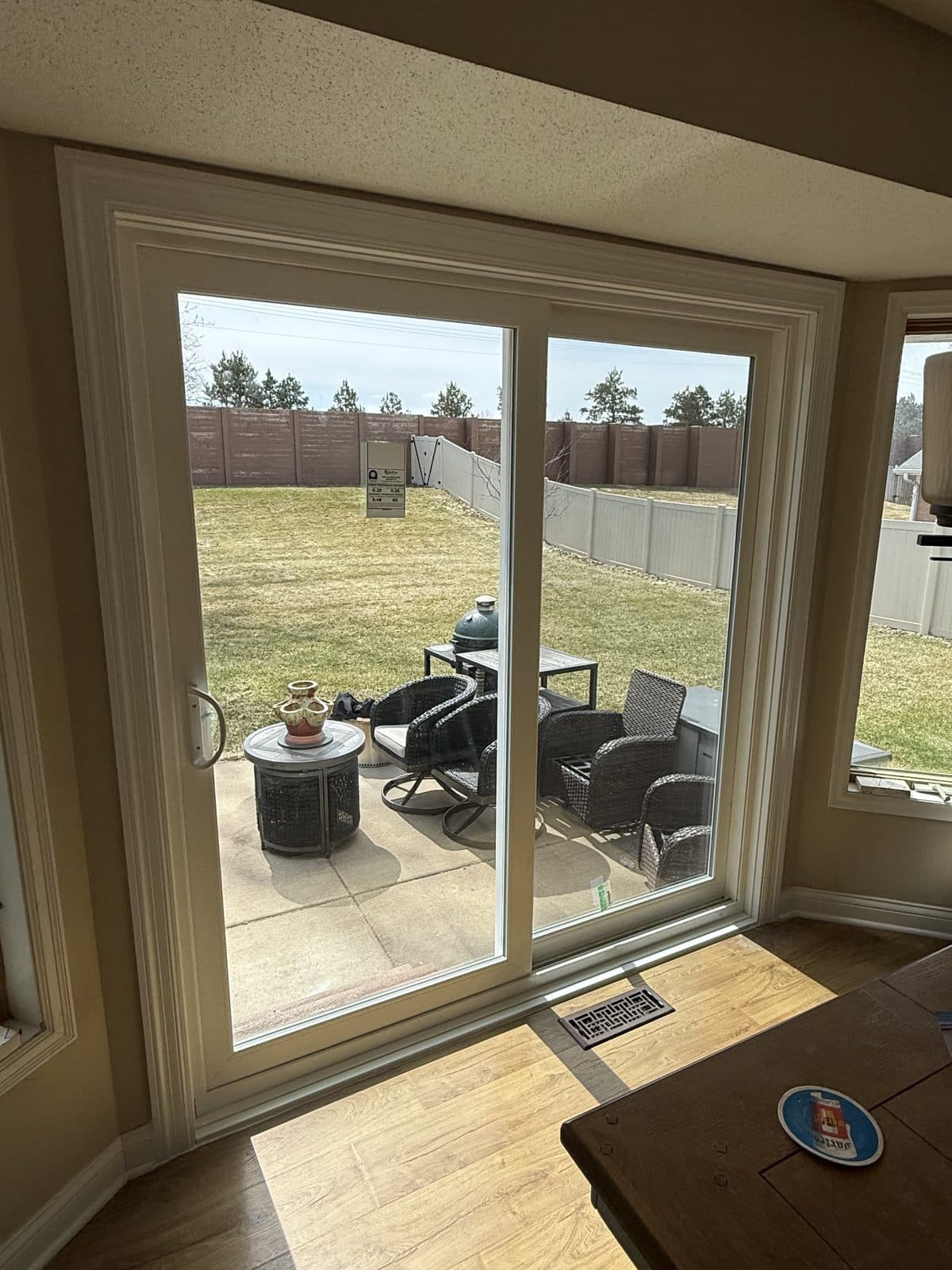 New white sliding patio door off a dining area, opening onto a fenced patio