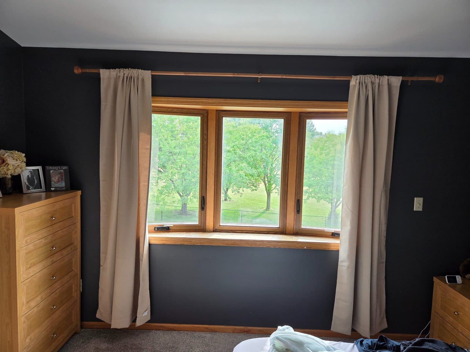 Triple casement window with oak trim in a bedroom with dark walls