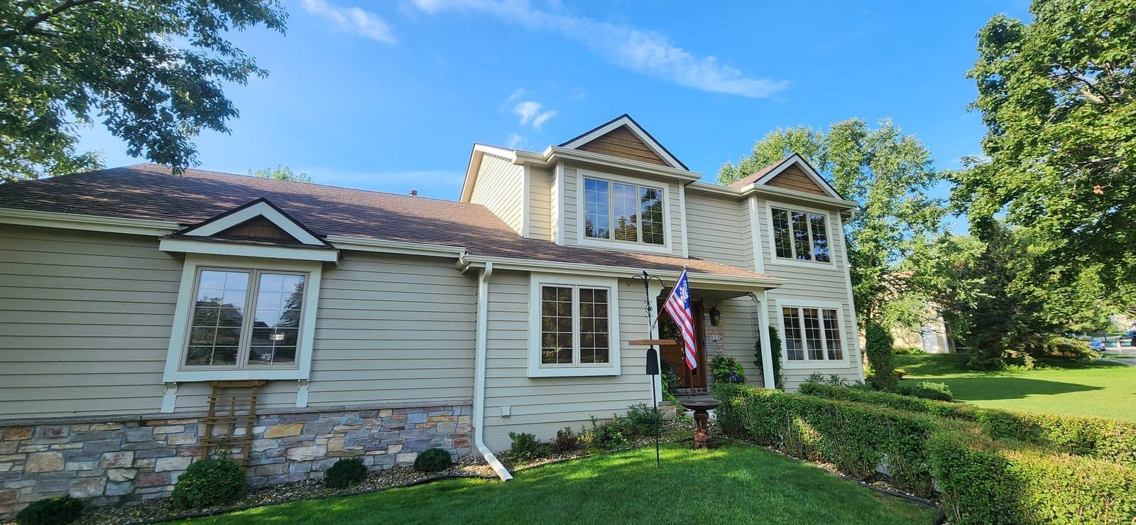 Sunny two-story Minnesota home with a full set of new white grid windows and stone accents